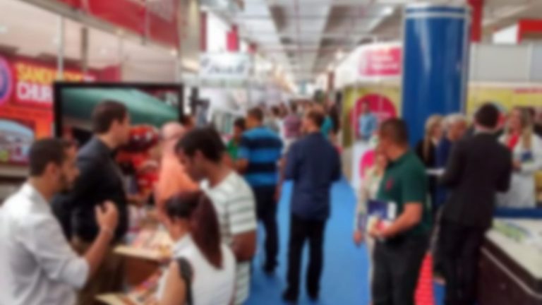 Foto desfocada ilustra a matéria sobre a 1ª Feira de Negócios de Guanambi com um corredor de uma feria de negócios