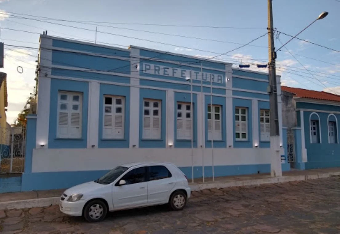 Foto mostra fachada da Prefeitura de Morro do Chapéu. Há um automóvel branco estacionado em frente ao imóvel - Processo Seletivo da Prefeitura de Morro do Chapéu