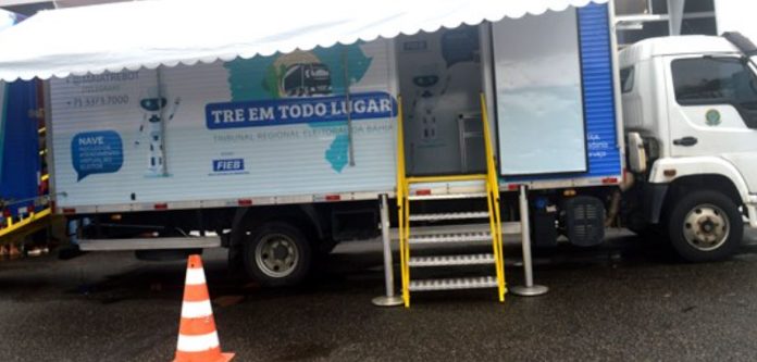 Foto mostra um caminhão cuja a carroceria foi adaptada e personalizada com a logomarca do programa TRE em todo lugar para o atendimento dos eleitores junto ao órgão.