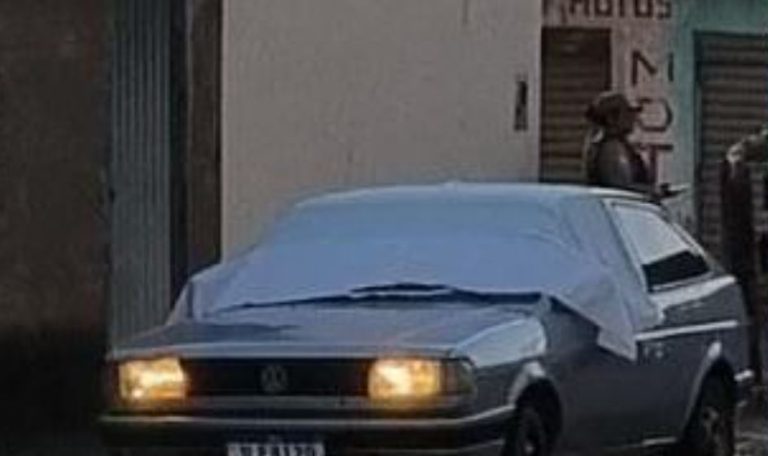 Foto mostra veículo onde corpo foi encontrado e policiais militares ao fundo