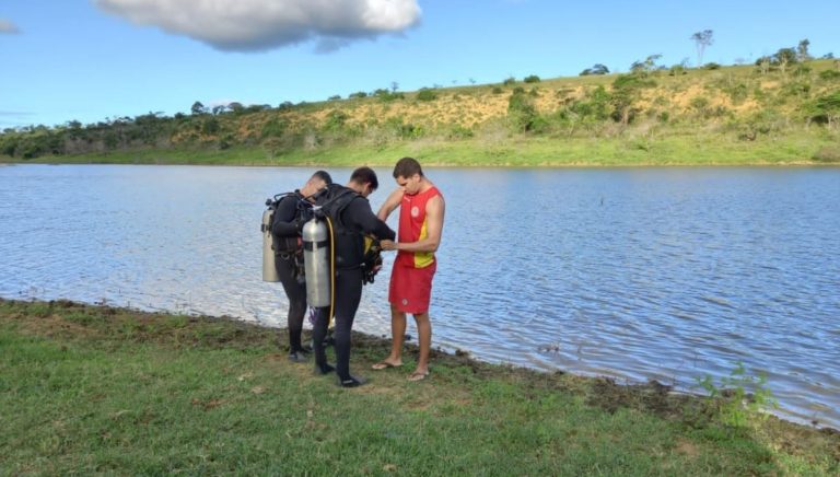 Foto mostra mergulhadores dos bombeiros às margens da lagoa onde foi encontrado o corpo
