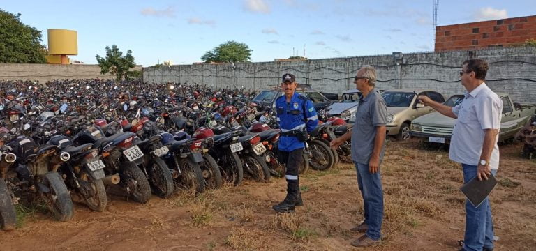 Foto mostra três servidores da SMTran em frente a automóveis retidos no pátio