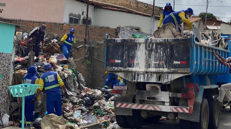 Foto mostra uma caçamba sendo carregada em frente ao imóvel onde foram recolhidos os materiais
