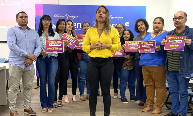 Foto mostra conselheiros do Coren-BA segurando plaquinhas pedindo a reaberturas das unidades