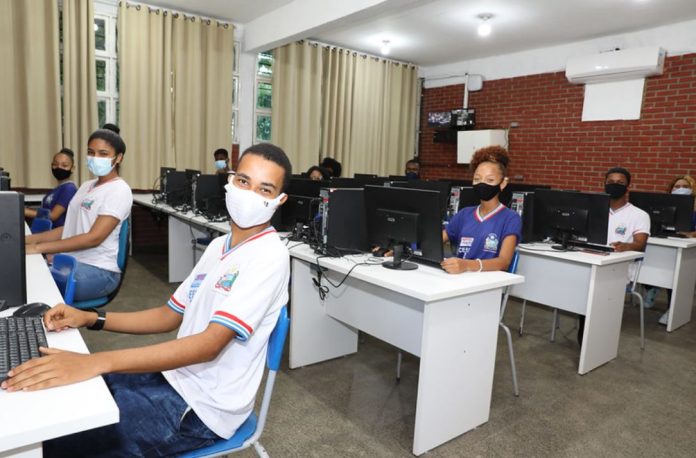Foto mostra estudantes em uma laboratório de informática