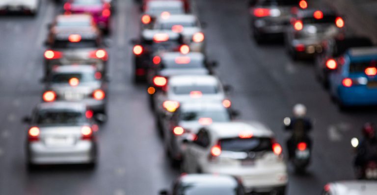 Foto desfocada mostra uma fila de veículos em uma rodovia