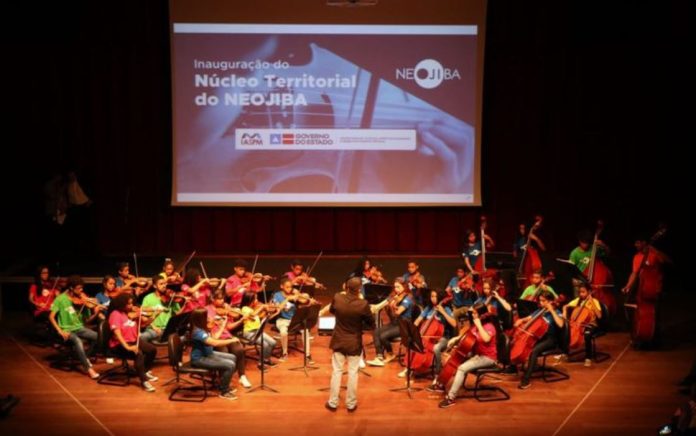 Foto mostra apresentação da orquestra em um palco