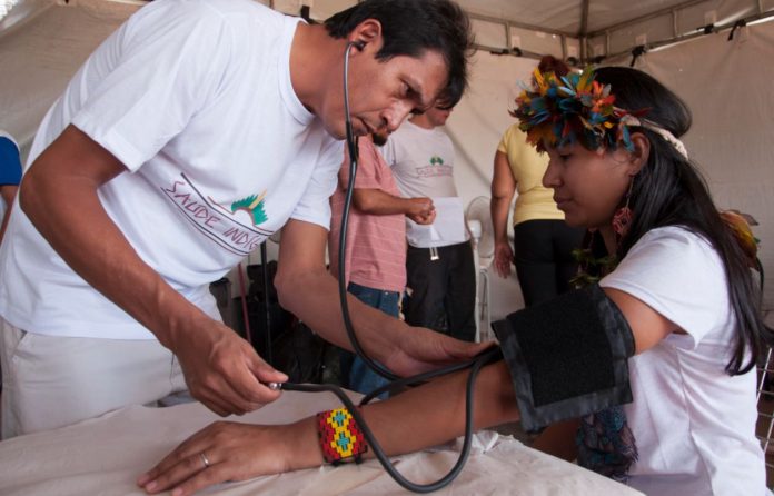 Foto mostra profissional de saúde medindo a pressão arterial de uma indígena - Processo seletivo do Imip