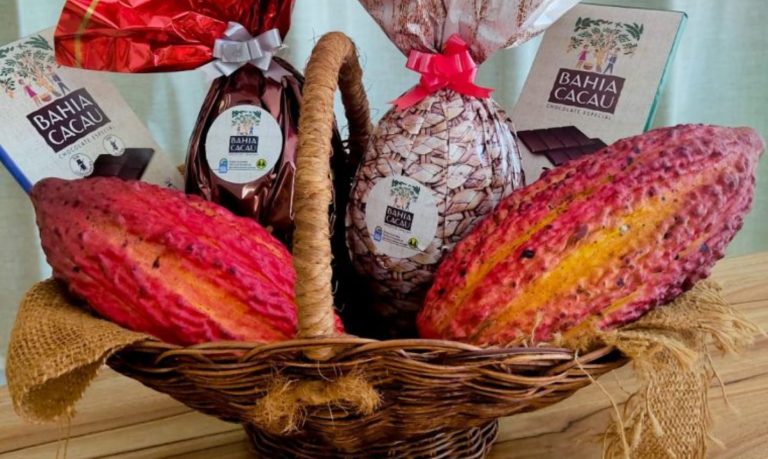 Foto mostra uma cesta com chocolates, ovos de páscoa e duas unidades de cacau