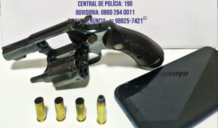 Foto mostra a arma, o celular e as munições apreendidas