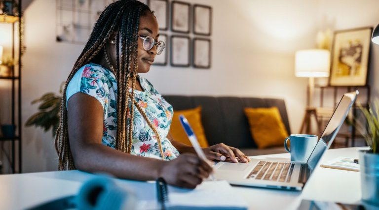 Foto mostra uma mulher estudando em frente a um computador