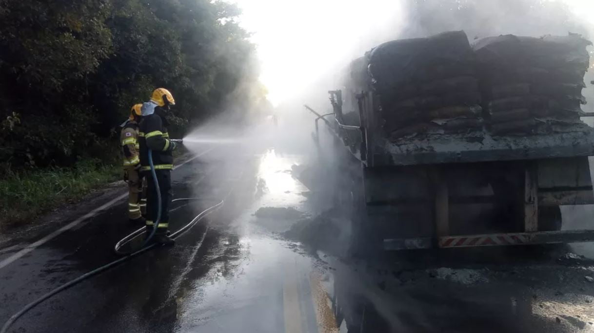 Foto mostra bombeiros combatendo chamas na carreta