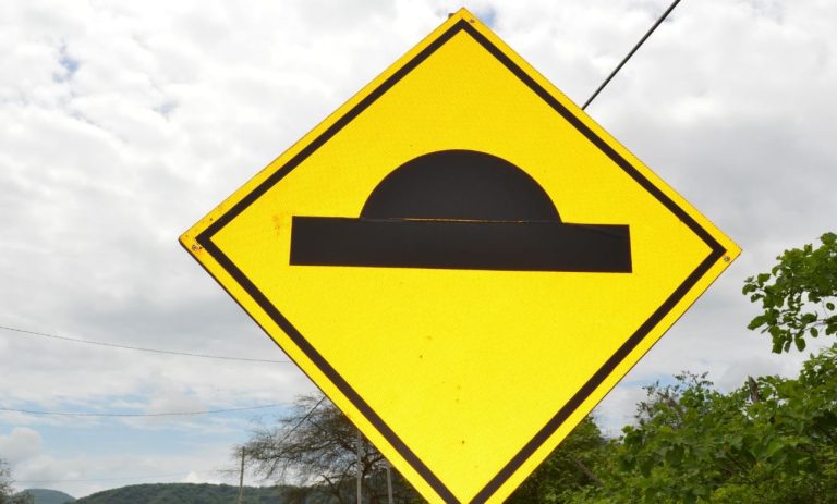 Foto mostra uma placa de trânsito indicando um queba-molas