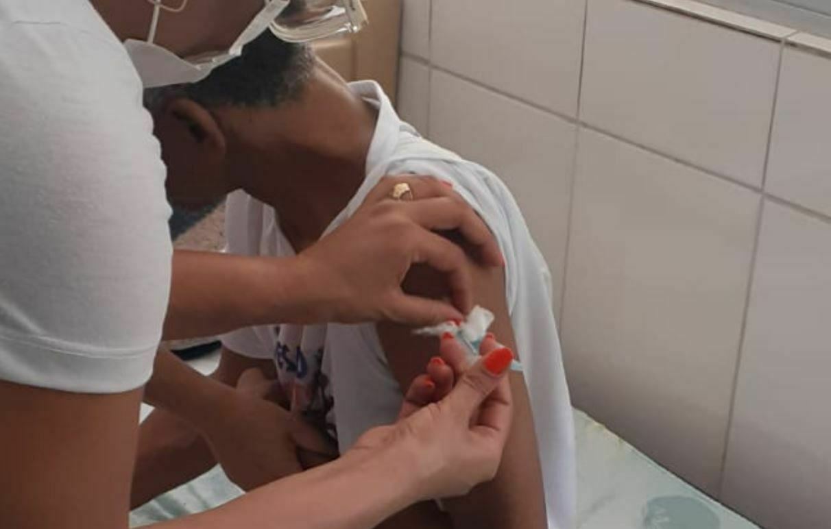 Foto mostra profissional de saúde aplicando uma vacina em um idoso