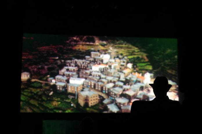 Imagem mostra uma sala de cinema com um mapa na tela