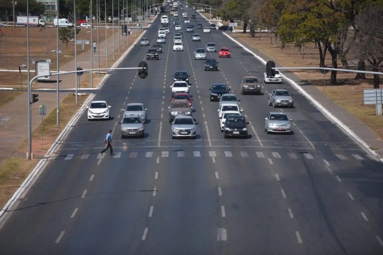 Pessoa atravessando avenida movimentada pela faixa de pedestre
