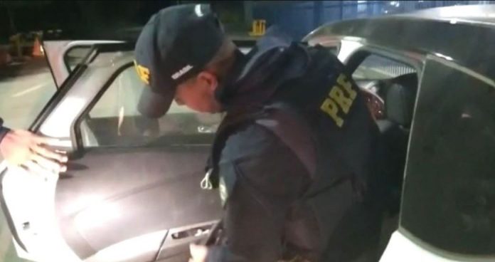 Policial rodoviário federal revistando carro em busca de drogas