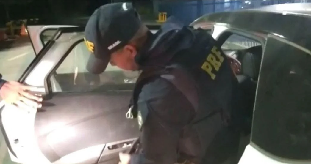 Policial rodoviário federal revistando carro em busca de drogas